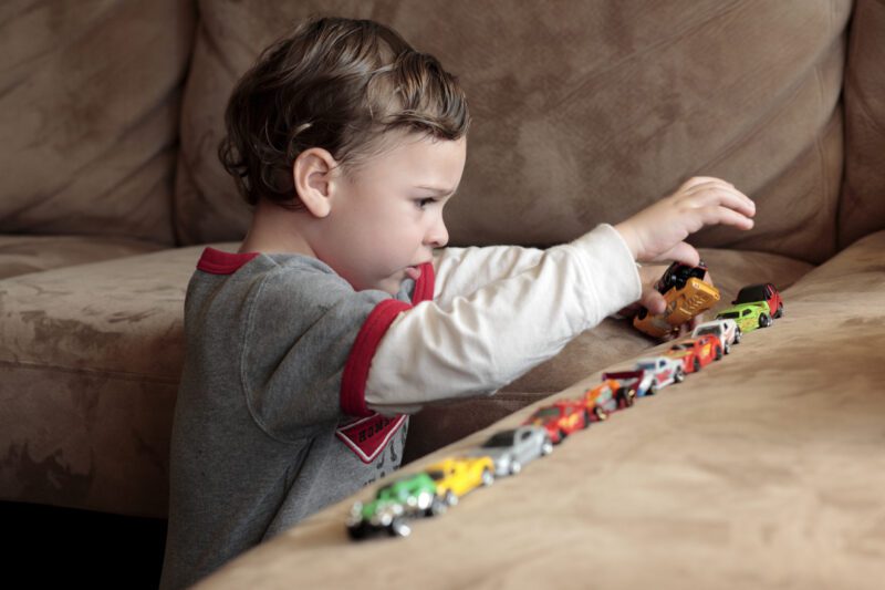 An autistic child playing with colorful cars